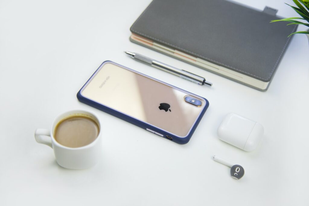 Smartphone with cup of coffee and earbud on table